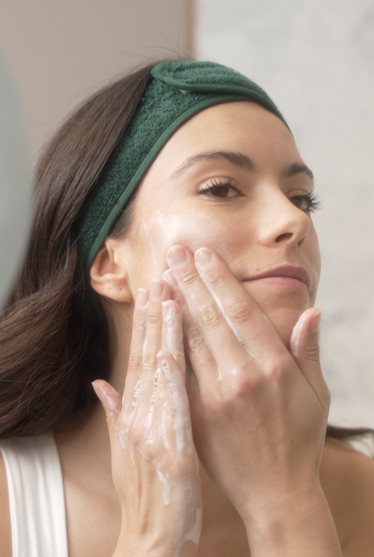 Femme se mettant du nettoyant trio d'huiles sur le visage poudre qui se transforme en mousse